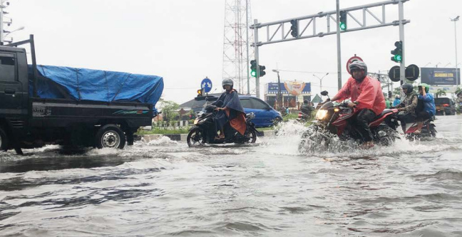 SEMPAT NAIK: Pengendara melintas di dekat perempatan Karanglo, Kecamatan Karangploso yang kebanjiran akibat hujan deras, kemarin. YUDHISTIRA/RADAR MALANG