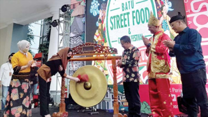 EVENT RUTIN: Arumi Bachsin, istri Wagub Jatim memukul gong sebagai tanda peresmian Batu Street Food Festival 2022 yang dibuka kemarin (11/11). (AFIFAH RAHMATIKA/RADAR BATU)