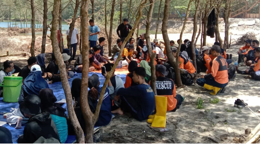 LAKUKAN IKHTIAR: Para relawan beristirahat sambil makan siang usai membersihkan sisa material banjir di Pantai Bajulmati, Kecamatan Gedangan, kemarin (30/10). BSTC FOR RADAR MALANG