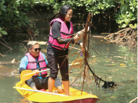 JAGA HUTAN MANGROVE: Lia Putrinda (kanan) membersihkan sampah yang terbawa aliran sungai di kawasan CMC Tiga Warna, Sumbermanjing Wetan