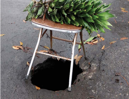 AWAS ADA LUBANG: Kursi yang dipasang warga di Jalan Bandung menjadi penanda karena ada kerusakan.