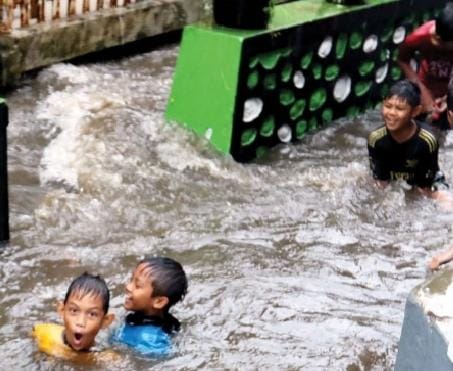 BANJIR LAGI: Bocah-bocah berenang di ruas Jalan Bareng Gang 2, Kelurahan Bareng, Kecamatan Klojen yang digenangi air hujan. (DARMONO/RADAR MALANG)