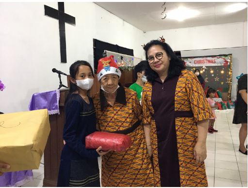 DOORPRIZE: Ketua RAAL Griya Asih Natalie P Pouluan (kanan) mendampingi salah satu oma penghui panti menyerahkan doorprize kepada salah satu undangan yang beruntung di acara Peringatan Natal dan tahun baru tadi sore, Kamis (22/12/2022).