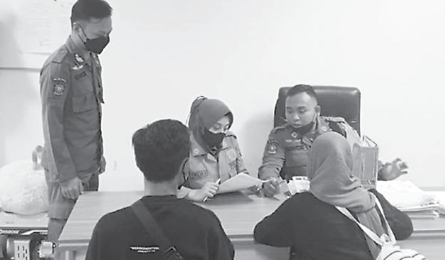 WAJIB LAPOR: Petugas Satpol PP Kota Malang mendata identitas pasangan yang terciduk sedang bermesraan di Alun-Alun Merdeka pada Rabu malam (16/12).