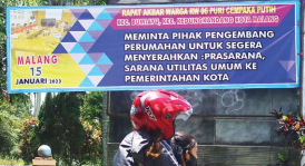 AKSI PROTES: Warga RT 06 Puri Cempaka Putih 2 memasang poster berisi desakan agar pengembang segera menyerahkan PSU ke Pemkot Malang.