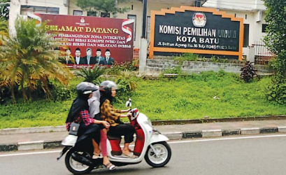 SAMBUT PEMILU: Pengendara sepeda motor melintas di depan Kantor KPU Kota Batu. (afifah/radar malang)