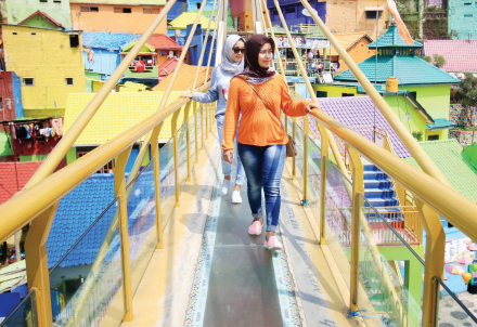 WISATA KAMPUNG: Wisatawan Kampung Warna-Warni Jodipan menikmati keindahan rumah penduduk  dari jembatan kaca, kemarin. Tahun ini Pemkot Malang berencana melakukan rebranding kampung.