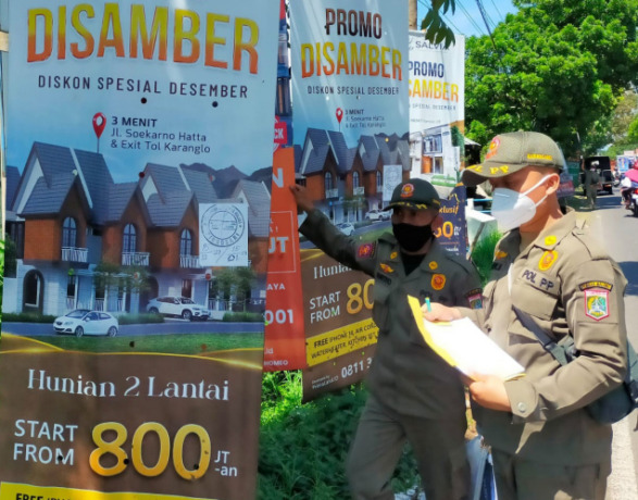 DITURUNKAN PAKSA: Petugas Satpol PP Kabupaten Malang menertibkan reklame yang melanggar peraturan daerah di kawasan Karangploso.