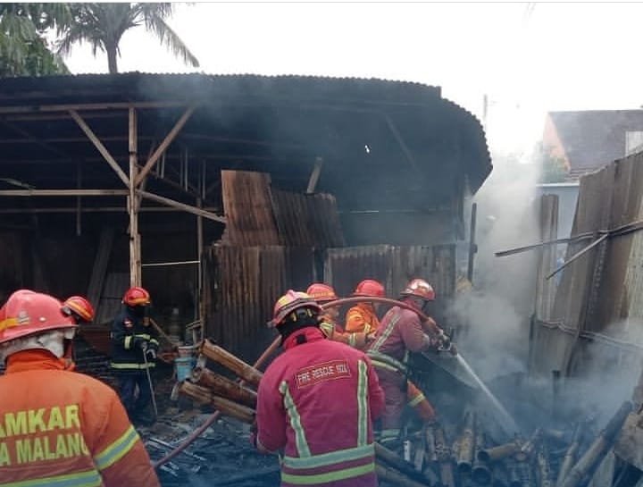 AKIBAT LALAI: Petugas Damkar Kota Malang melakukan pembasahan setelah seluruh bagian gudang yang terbakar berhasil dipadamkan. Mereka mengerahkan 16 personel, 3 mobil damkar, dan menyemburkan sekitar 5 ribu liter air. - UPT DAMKAR KOTA MALANG FOR RADAR MA