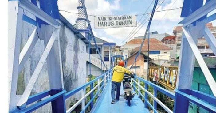 WAJAH BARU: Seorang pengendara menuntun motornya saat melintasi Jembatan Oro-Oro Dowo Gang XIII, kemarin.- SUHARTO/RADAR MALANG