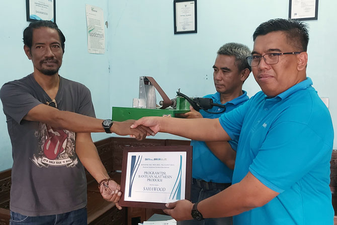 SINERGI: Mochammad Theo Zainuri (kiri) menerima bantuan alat produksi dan bahan kayu dari PT Berdikari Meubel Nusantara. (BIYAN MUDZAKY HANINDITO/RADAR MALANG)