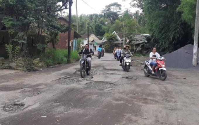 KAPAN DIPERBAIKI:: Warga melintas di Jalan Lesti, Kecamatan Wajak yang kondisinya rusak.(INDAH MEI YUNITA/RADAR MALANG)