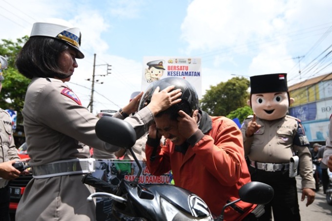 LANGSUNG DIPAKAI: Kasat Lantas Polres Malang AKP Agnis Juwita Manurung membagikan helm gratis kepada pengendara. (Darmono/Radar Malang)