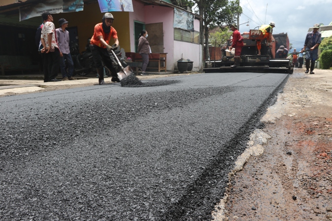 Sejumlah pekerja menuang aspal di jalan Binangun, Desa Genengan, Kecamatan Pakisaji. beberapa waktu lalu (Darmono/Radar Malang)