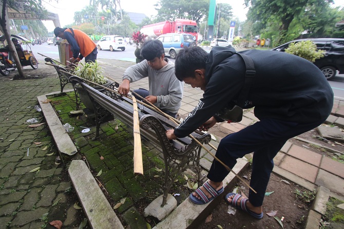 PASANG : Petugas DLH Kota Malang memasang bambu lagi untuk menyegel kursi pedestrian. (Suharto/Radar Malang)