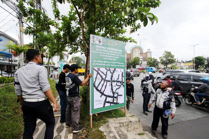 PASANG : Dishub Kota Malang memasang papan pengumuman ujicoba satu arah di pertigaan Avia PLN. (Suharto/Radar Malang)