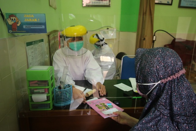 CEK KESEHATAN: Pasien menyerahkan buku kesehatan ibu dan anak ke tenaga kesehatan Puskesmas Kendalsari kemarin pagi (1/2).  (DARMONO/RADAR MALANG)