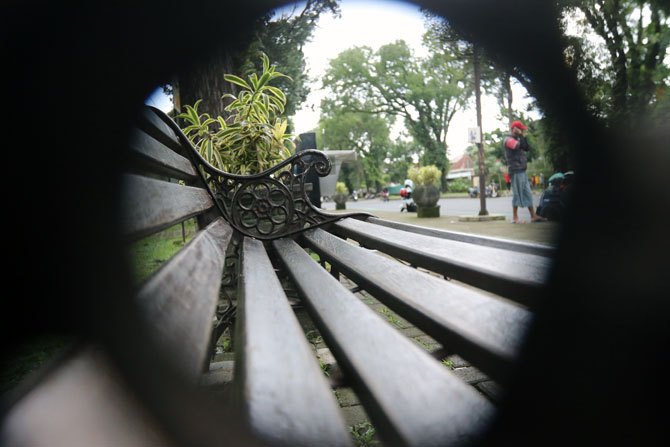 FASILITAS PUBLIK: Warga duduk bersantai di kursi taman Ijen yang tidak bersegel kemarin (14/2). DLH Kota Malang menduga, segel tersebut sengaja dirusak oleh orang yang tidak bertanggung jawab.(Darmono/Radar Malang)
