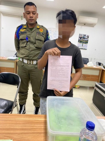 PUTUS SEKOLAH: Bocah penjual donat menunjukkan surat pernyataan tidak akan mengulangi perbuatan sebelum dikembalikan kepada keluarganya pada Senin malam (13/3). (SATPOL PP KOTA MALANG FOR RADAR MALANG )