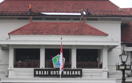 BERSOLEK: Tiga pekerja memasang seng di atap gedung Balai Kota Malang kemarin (14/3). Rencananya juga akan dipasang lampu hiasan di sekeliling gedung.