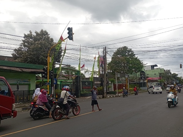 DIATUR SUPELTAS: Sukarelawan pengatur lalu lintas (Supeltas) mengarahkan pengendara yang melintas di pertigaan PLN Kepanjen. (Hanif/Radar Malang)