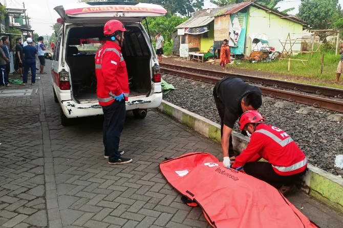 LUKA PARAH: Anggota PMI dan relawan mengevakuasi jenazah Siti yang tertabrak KA Brawijaya di Kelurahan Ciptomulyo, Kecamatan Sukun, kemarin pagi (20/3). (PMI for Radar Malang)