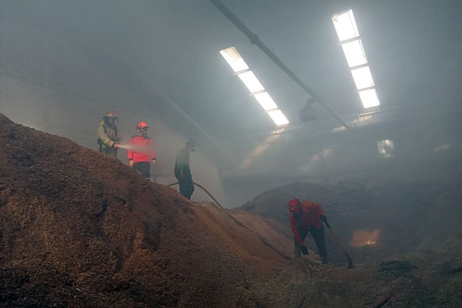 JINAKKAN API: Personel Damkar Kabupaten Malang memadamkan api di antara asap pabrik wood pellet Desa Ardimulyo, Kecamatan Singosari, Kabupaten Malang kemarin (6/3).(Satpol PP Kabupaten Malang for Radar Malang)