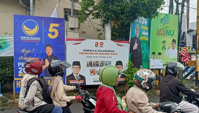 BERTEBARAN: Empat spanduk dari berbagai parpol terpasang di Simpang Empat Kasin, Kecamatan Klojen, kemarin. (suharto/radar malang)