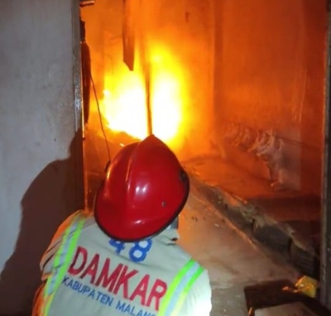 DARI DAPUR PRODUKSI: Petugas Damkar Kabupaten Malang menyemprotkan air ke bagian dapur produksi tahu yang terbakar di Desa Gedog Wetan, Kecamatan Turen. (Damkar Kabupaten Malang for Radar Malang)