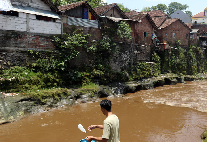 TERTANGKAP KAMERA : Seorang pria terlihat membuang bungkusan plastik ke sungai, di wilayah Polehan, Oktober 2022 lalu. (Darmono/Radar Malang)