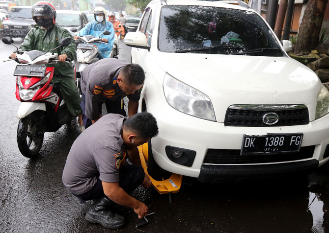 BERI EFEK JERA: Empat mobil yang kedapatan parkir sembarangan di Jalan Jaksa Agung Suprapto digembok petugas gabungan. (Darmono / Radar Malang)
