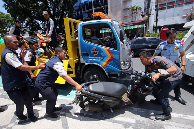 PENERTIBAN: Personel dishub Kota Malang mengangkut motor yang kedapatan parkir di zona terlarang.(Suharto/Radar Malang)