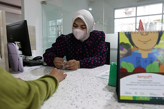 KEBUTUHAN RAMADAN: Pegawai PT Pegadaian Cabang Malang melayani masyarakat yang ingin menggadaikan emas.(Darmono/Radar Malang)
