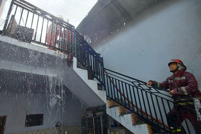 BILAS : Pemadam Kebakaran Kota Malang membasahi seluruh lantai dua rumah yang terbakar di Gadang, Kota Malang. (Biyan/Radar Malang)