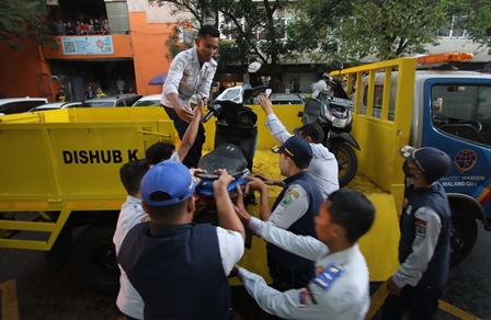 TINDAK TEGAS: Personel Dishub Kota Malang mengangkut kendaraan yang parkir sembarangan di area Pasar Besar Malang kemarin (5/4). (Darmono/Radar Malang)