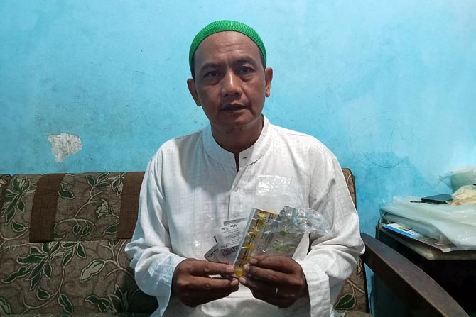 BARU KENA SERANGAN: Joko Budianto menunjukkan obat yang harus rutin dia minum setelah operasi pemasangan ring jantung.(NABILA AMELIA/RADAR MALANG)