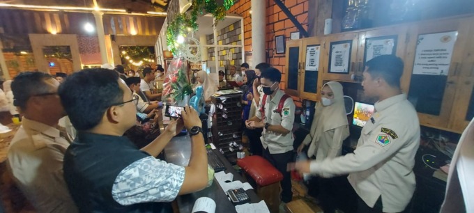CEK ULANG: Petugas Bapenda Kota Malang memeriksa jumlah transaksi salah satu rumah makan yang dikunjungi bersama Satpol PP pada Sabtu malam (8/4). (BIYAN MUDZAKY HANINDITO/RADAR MALANG)