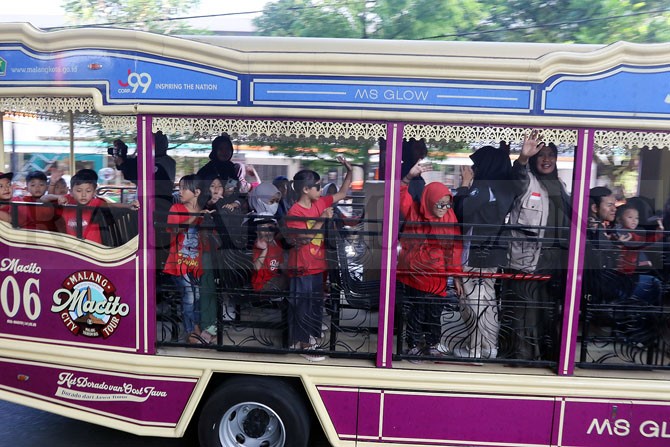 BAHAGIA: Puluhan anjal dan bocah penghuni rusunawa Buring naik bus Malang City Tour (Macito) kemarin (21/5). Mereka diajak mengelilingi sejumlah objek wisata di Kota Malang.(Darmono/Radar Malang)