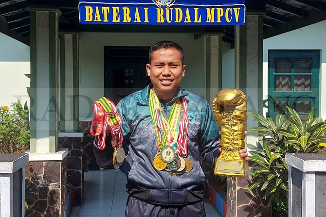 UKIR PRESTASI: Praka Pitono menggenggam puluhan medali dan piala sarung tinju di markas Yon Arhanud 2/ Alap-Alap Malang, Minggu lalu (28/5). (Biyan Mudzaky Hanindito / Radar Malang)