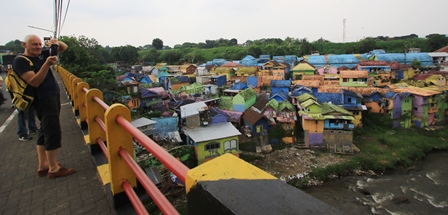 WISATAWAN ASING: Seorang wisatawan menikmati keindahan Kampung Warna-Warni Jodipan (WWJ) dari jembatan Embong Brantas kemarin (9/5). (Suharto/Radar Malang)