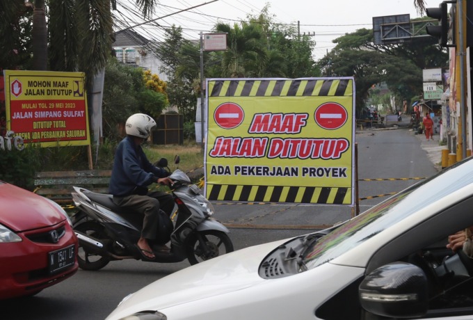 TUTUP SEMENTARA: Papan pemberitahuan penutupan jalan di Simpang Sulfat Utara, Kecamatan Blimbing, kemarin. Penutupan jalan dilakukan Pemkot Malang hingga Jumat depan demi memperlancar pembangunan drainase di sana. (darmono/radar malang)