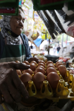 KURANG PASOKAN: Pedagang telur di Pasar Kebalen melayani pelanggannya. (Darmono/Radar Malang)