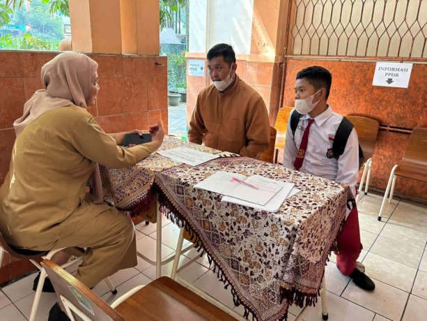 DIBURU PENDAFTAR: Seorang guru SMPN 3 Malang melayani Calon Peserta Didik Baru (CPDB) di hari kedua PPDB SMP jalur zonasi kemarin. (Fajar Andre/Radar Malang)