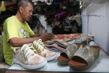 PRODUK LOKAL: Pengrajin sepatu Ridwan menunjukkan cara pembuatan sepatu eco print bermotif daun, kemarin. (Darmono/Radar Malang)