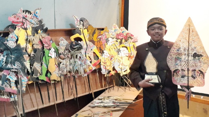 TERINSPIRASI KAKEK: Raihan Hisyam Atha Rifqi menunjukkan piala dan koleksi wayang di rumahnya, kemarin siang.(AFIFAH RAHMATIKA FURZAEN / RADAR MALANG)
