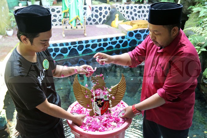 SIMBOL: Anggota Ikatan Pelajar Nahdlatul Ulama (IPNU) Desa Mangliawan melakukan prosesi jamasan terhadap simbol burung garuda di Sendang Widodaren Taman Wisata Wendit, Kecamatan Pakis, kemarin.(Darmono / Radar Malang)