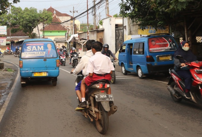 PASANG ATRIBUT: Dua stiker bacaleg dari parpol yang berbeda terpasang di kaca belakang angkot, kemarin siang.  (darmono/radar malang)
