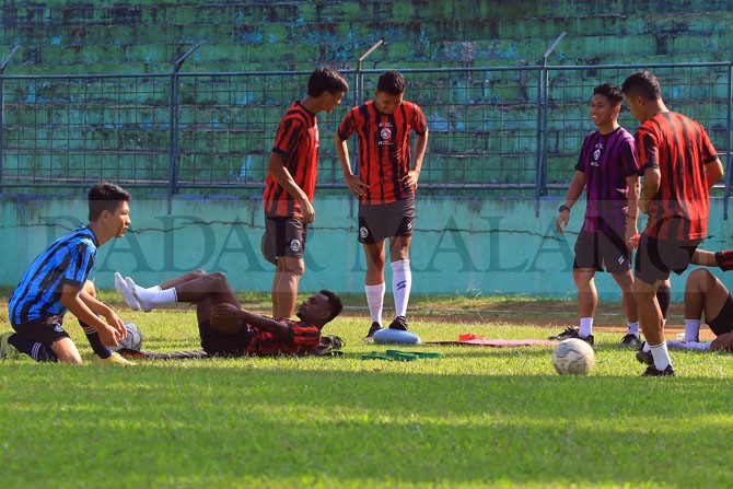 DIDAMPINGI TIM MEDIS: Jayus Hariono melakoni tahap penguatan di pinggir lapangan Stadion Gajayana, kemarin. Selain dia, ada empat penggawa Arema FC lainnya yang harus menepi. (Suharto / Radar Malang)
