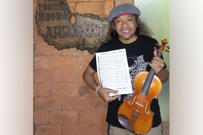 MUSISI: Sugiarto menujukkan lembaran berisi syair lagu ciptaannya, Minggu malam (5/6). (Sugiarto for Radar Malang)