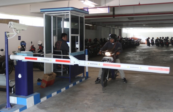 BARU DIPASANG: Pengendara sepeda motor membayar uang parkir kepada petugas e-parking di area basement Gedung MCC, kemarin siang. (darmono/radar malang)
